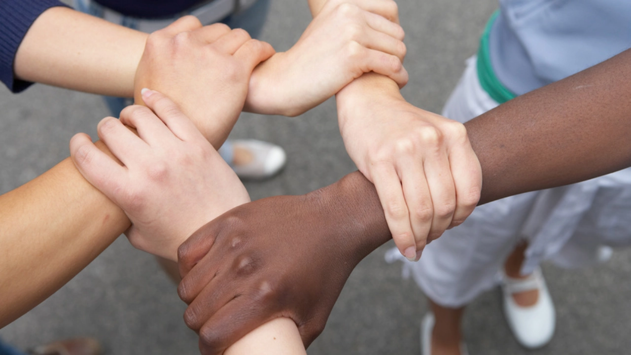 5 Hände internationaler Herkunft halten sich gegenseitig