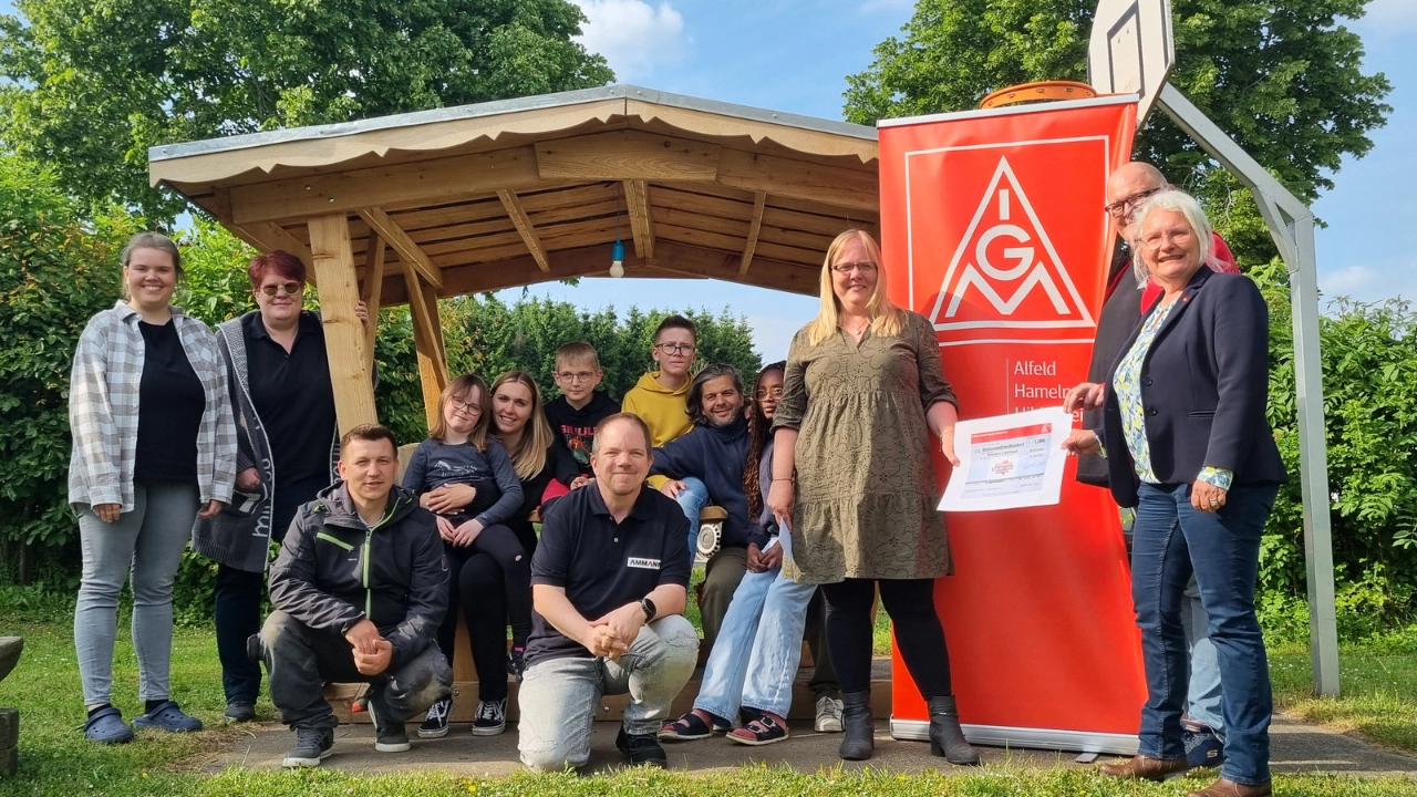Thomas Ergezinger, Phoenix Contact (2.v.re.) und Karoline Kleinschmidt (re.) überreichen Katrin Tutsch-Watermann (3. v. re.) gemeinsam mit Marcus Van Son, Ammann ABG (kniend, Bildmitte) und Iris Ergezinger, Phoenix Contact (2. V. li.) im Beisein der Kinder und Jugendlichen sowie den Mitarbeitern des Kunterbunt e. V. den symbolischen Spendenscheck.