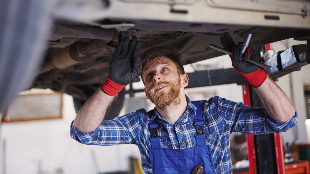 Ein Kfz-Mechaniker prüft den Unterboden eines Autos
