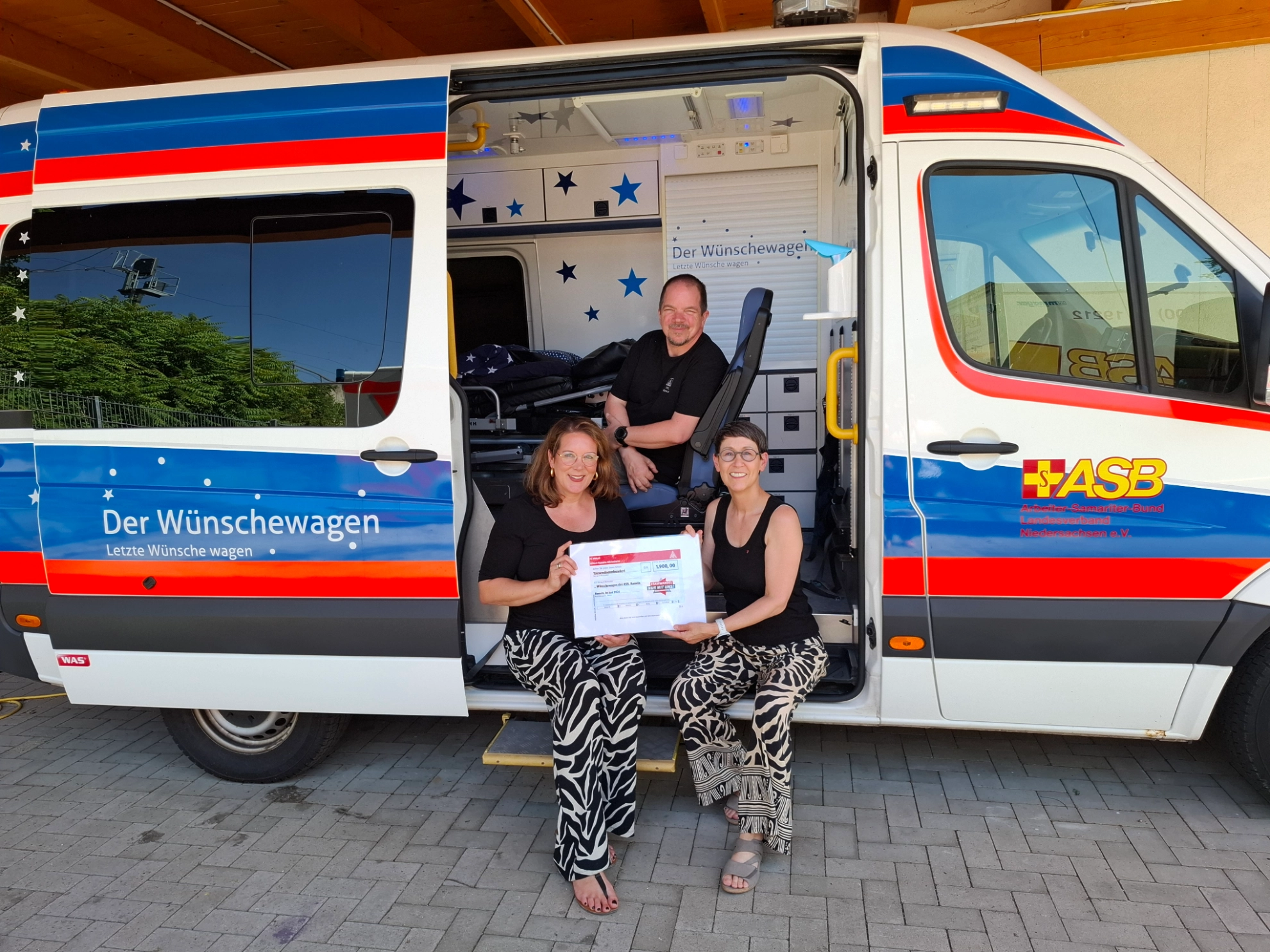  Frau Julia-Marie-Meisenburg (li.) vom Projekt Wünschewagen des ASB nimmt die Spende von Bianka Möller (re.) und Markus Son, Ammann ABG, entgegen. Foto: IG Metall.<br/>