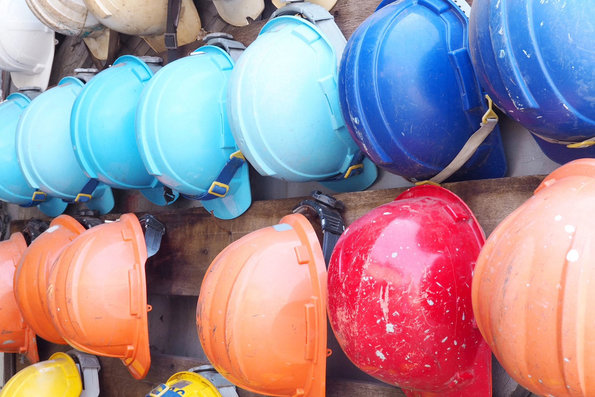 Schutzhelme in verschiedenen Farben, die an einer Wand hängen.